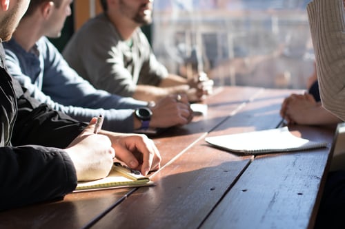 men sitting at table writing